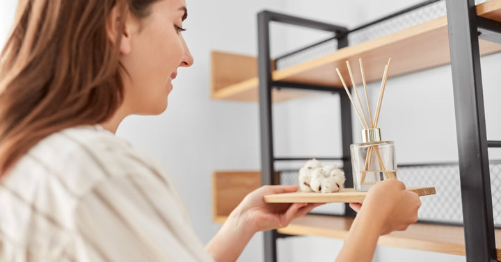 A young homeowner and aromatherapy user placing a reed diffuser and diffuser cotton balls onto a shelf in her home.